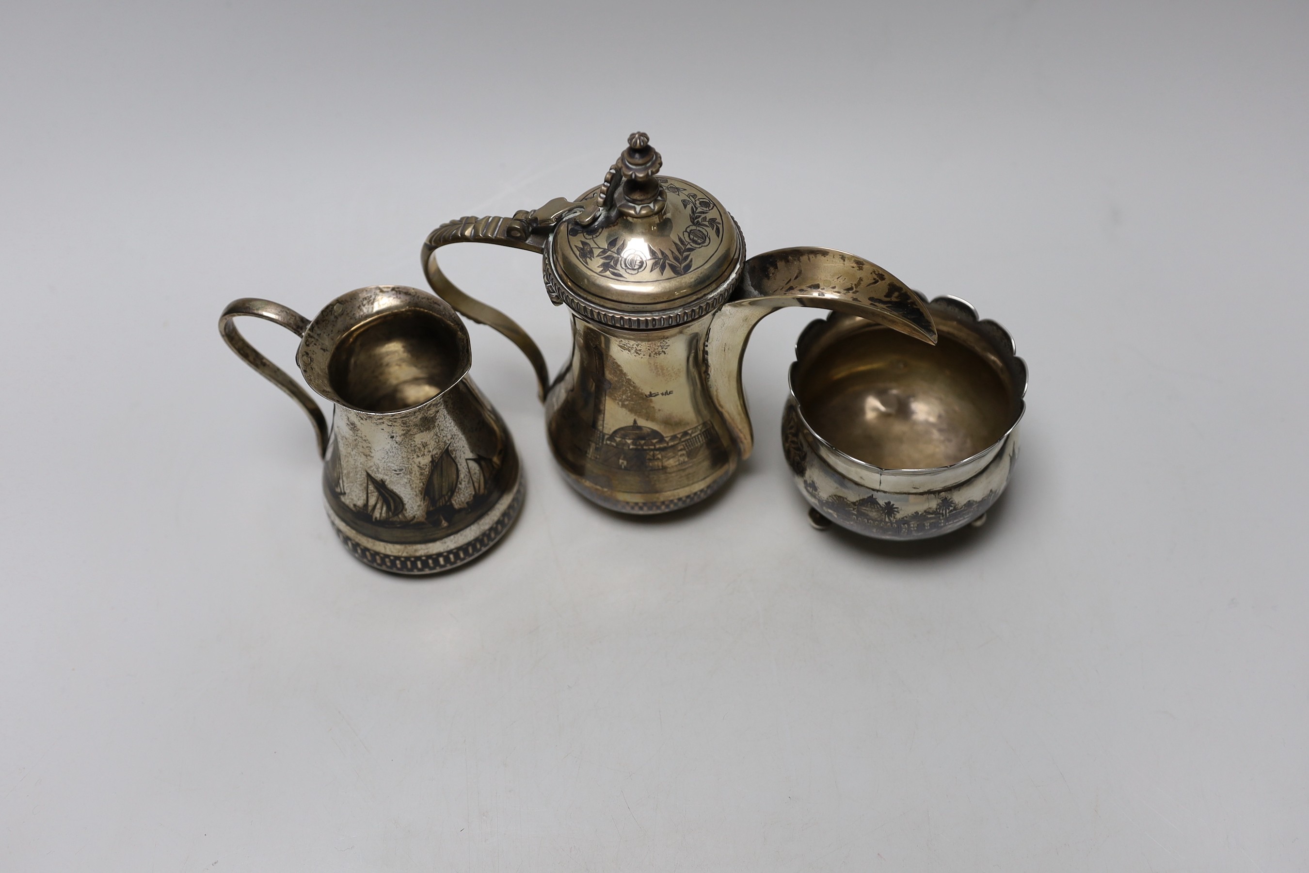 A Middle Eastern white metal and niello cream jug, a sugar bowl and coffee pot, 16.4cm, gross weight 22oz.